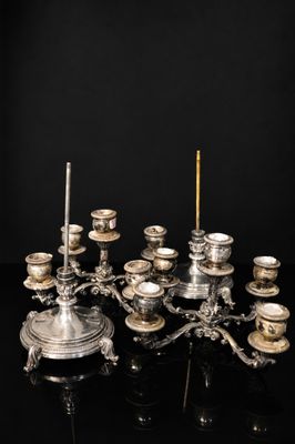 un candélabre en métal plaqué argent avec des bougies posées sur un socle noir