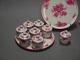 a pink and white plate and cups and saucers