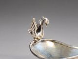 a silver spoon with a bird on top of it