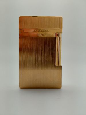 une photo d'un briquet doré posé sur une table blanche