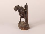 a bronze statue of a dog holding a book on a wooden base