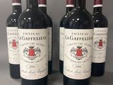 quatre bouteilles de vin rouge sont alignées sur une table