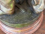 a bronze statue of a person standing on a wooden table