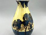 un vase bleu et jaune posé sur une table