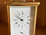 une horloge en or posée sur une table en bois devant un mur
