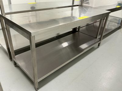une grande table en acier inoxydable au milieu d'une pièce