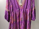 a purple blouse hanging on a hanger on a wall