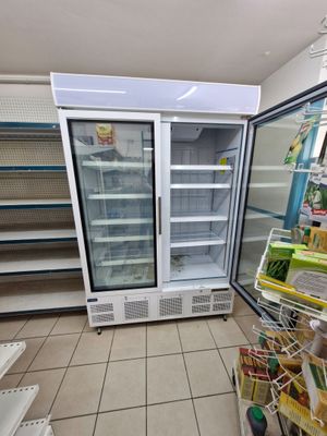 an empty refrigerator in the middle of a grocery store
