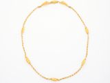 un bracelet en chaîne d'or orné d'une perle dorée sur fond blanc