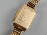 a close up of a gold watch with a chain around it