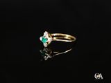 un gros plan d'une bague en or sertie d'une émeraude et d'un diamant blanc