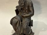 bronze statue of a man sitting on a chair with a book in his lap