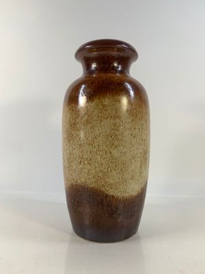 un grand vase marron posé sur une surface blanche