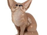 a small ceramic figurine of a cat sitting on a white surface