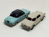 two toy cars sitting next to each other on a white surface