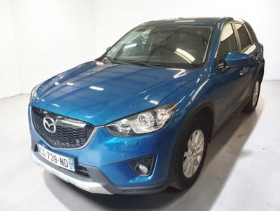 La Mazda CX-HR bleue est garée dans une pièce blanche