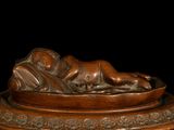 bronze statue of a woman laying on a plate on a black background