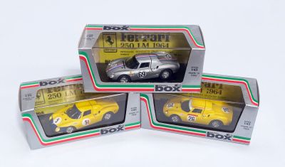 trois boîtes contenant des petites voitures posées sur une surface blanche