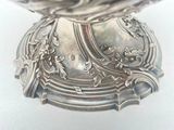 a silver bowl on a white surface with gold coins in it