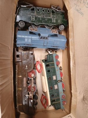 many toy trains in a cardboard box on the floor