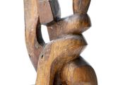 wooden sculpture of a seated man holding a piece of wood