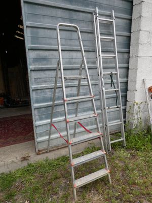 several ladders leaning up against a wall in front of a garage