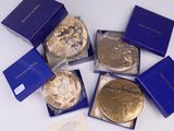 Plusieurs pièces d'or se trouvent dans une boîte bleue posée sur une surface blanche