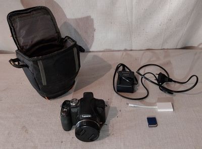 un appareil photo, un téléphone portable et un sac pour appareil photo posés par terre