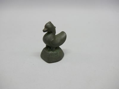 un gros plan sur une petite statue représentant un canard posé sur un rocher