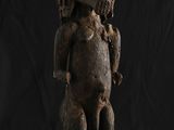 une statue en bois représentant un chien à la tête et aux pattes imposantes
