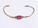 a close up of a bracelet with a pink stone on it
