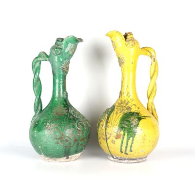 une paire de vases verts et jaunes posés l'un à côté de l'autre sur une surface blanche