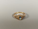 a close up of a gold ring with a blue topaz stone