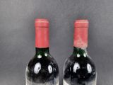 two bottles of red wine sitting next to each other on a table