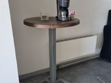 une petite table sur laquelle se trouve une cafetière, dans un coin de la pièce
