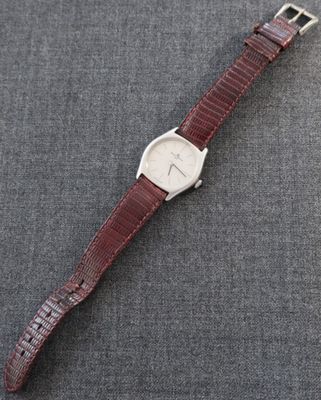 un gros plan d'une montre posée sur une surface grise