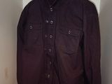 une chemise suspendue à un cintre dans une armoire où se trouvent d'autres vêtements