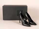 une paire de chaussures noires à talons hauts posée devant une boîte noire
