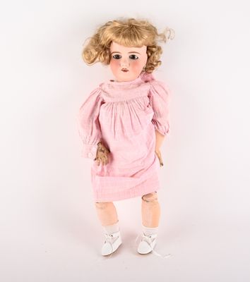 poupée aux cheveux blonds, vêtue d'une robe rose et de chaussures blanches, sur fond blanc