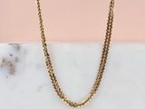 un collier à chaîne en or posé sur une surface en marbre