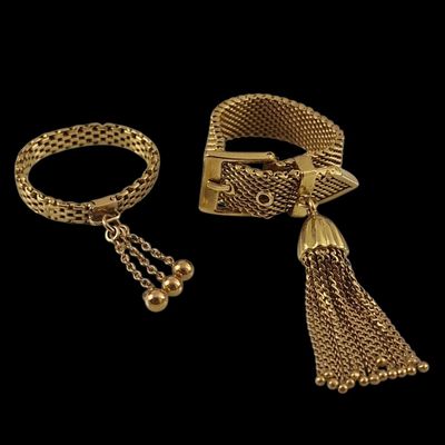two gold bracelets and a bracelet with a tassel on a black background