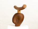 wooden sculpture of a bird sitting on top of a white pedestal