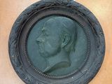 a bronze portrait of a man in a round frame