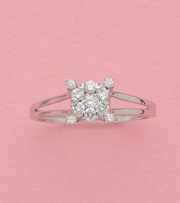 un gros plan d'une bague en diamant sur fond rose