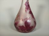 a purple vase with red flowers on it on a white surface