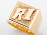 un gros plan d'une bague en or sur laquelle figure la lettre « r »