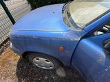 une voiture bleue qui a été endommagée et qui est garée dans la poussière