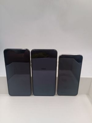 trois iPhones noirs posés sur un comptoir blanc
