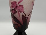 un vase orné d'une fleur rose, posé sur un socle noir