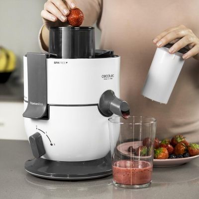 Quelqu'un met des fraises dans un mixeur avec un verre de jus.